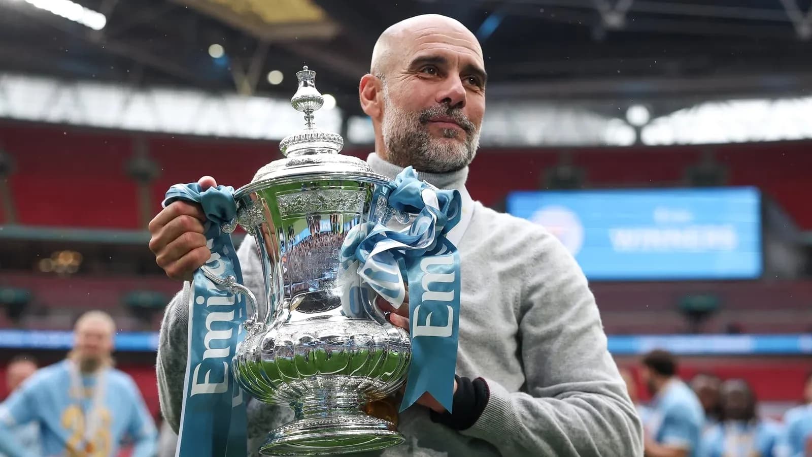 Тренер держит трофей на стадионе Wembley