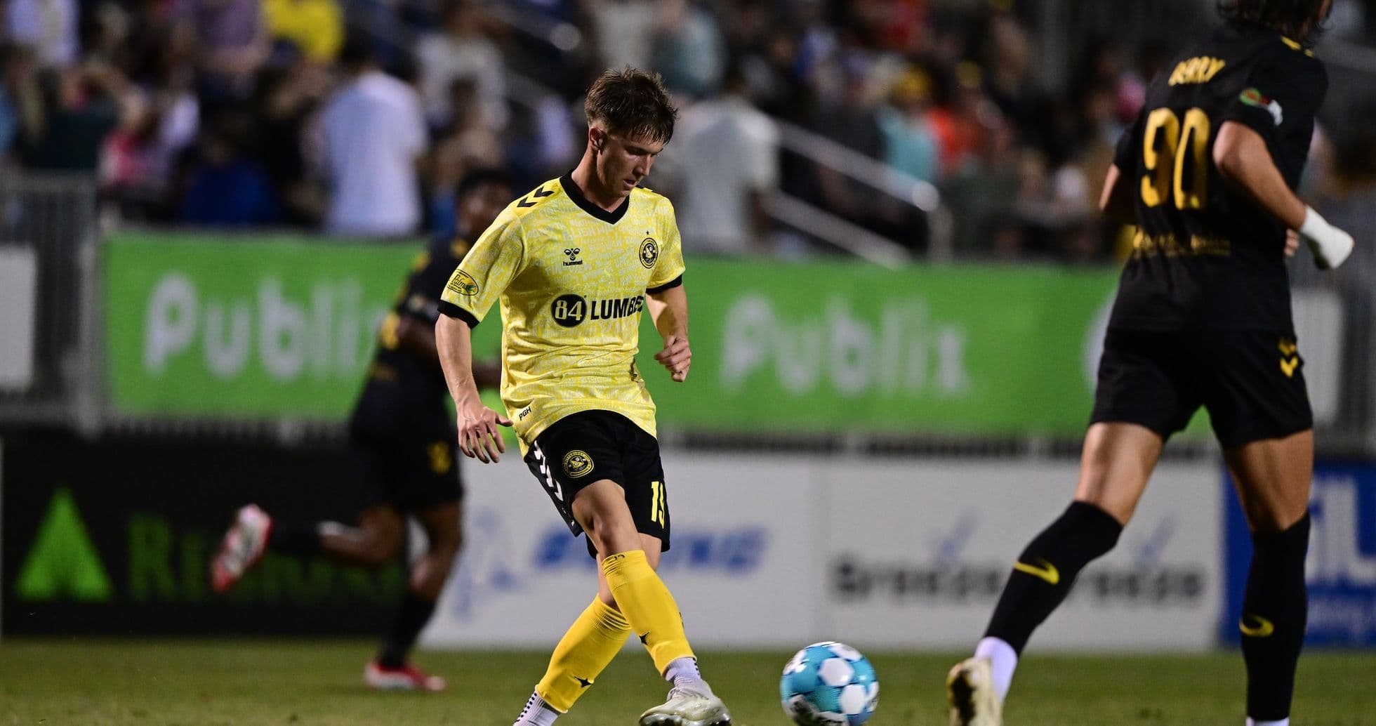 Игрок Charleston Battery в желтой форме с мячом Игрок Charleston Battery в желтой форме с мячом