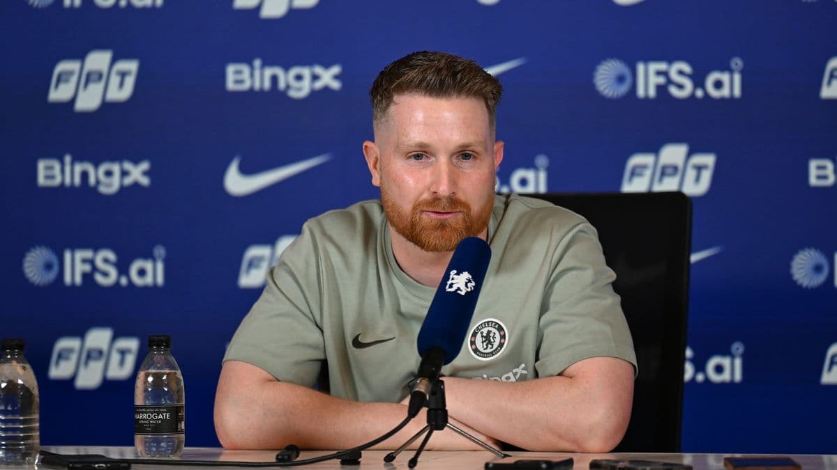Человек на пресс-конференции с логотипом Chelsea Человек на пресс-конференции с логотипом Chelsea